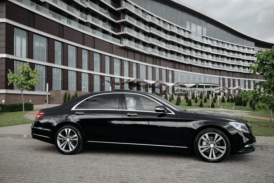 Elegant black sedan parked in front of a modern architectural building, showcasing luxury and style.